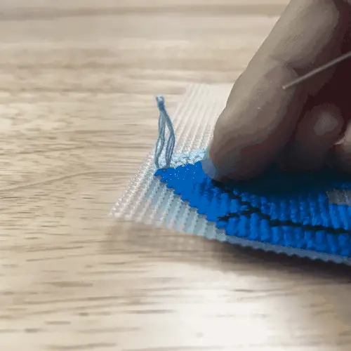 Blue embroidery floss forms a tiny loop over a knot.