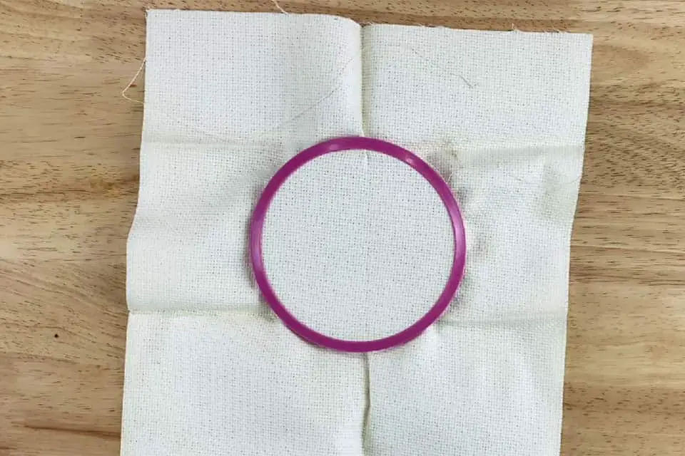 white fabric in a purple screw tension embroidery hoop