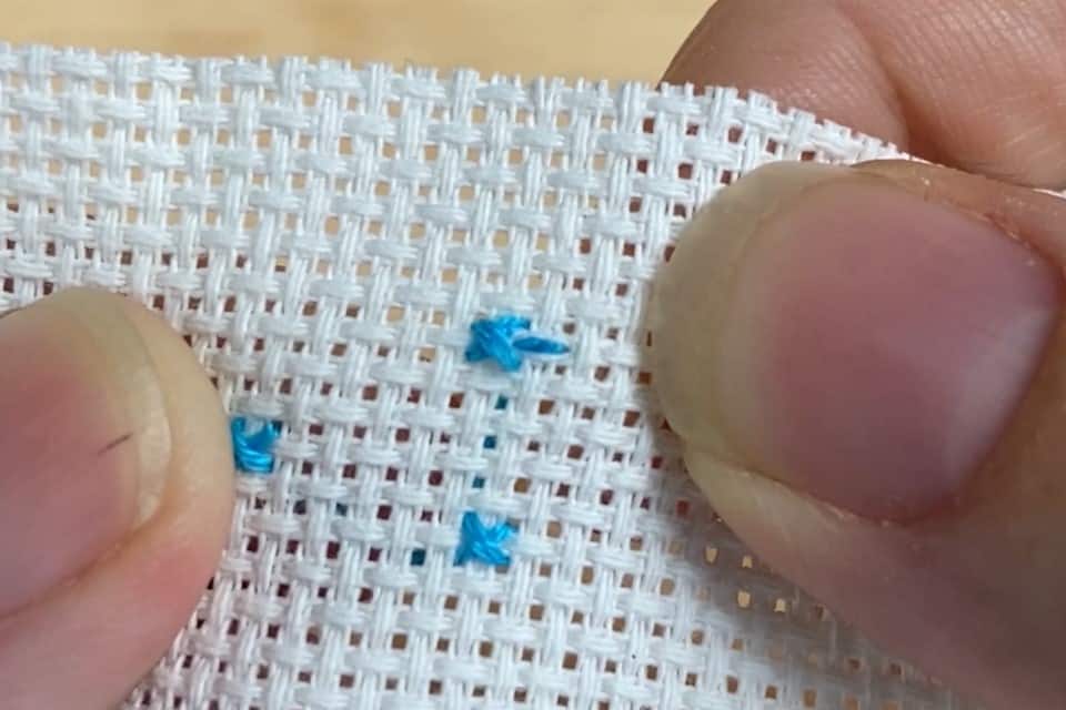 Three small blue cross stitches and a pin stitch 