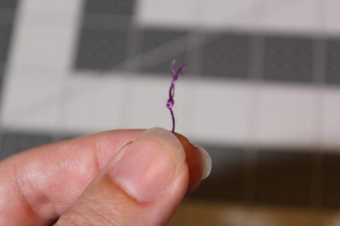 a knot is tied in purple embroidery floss